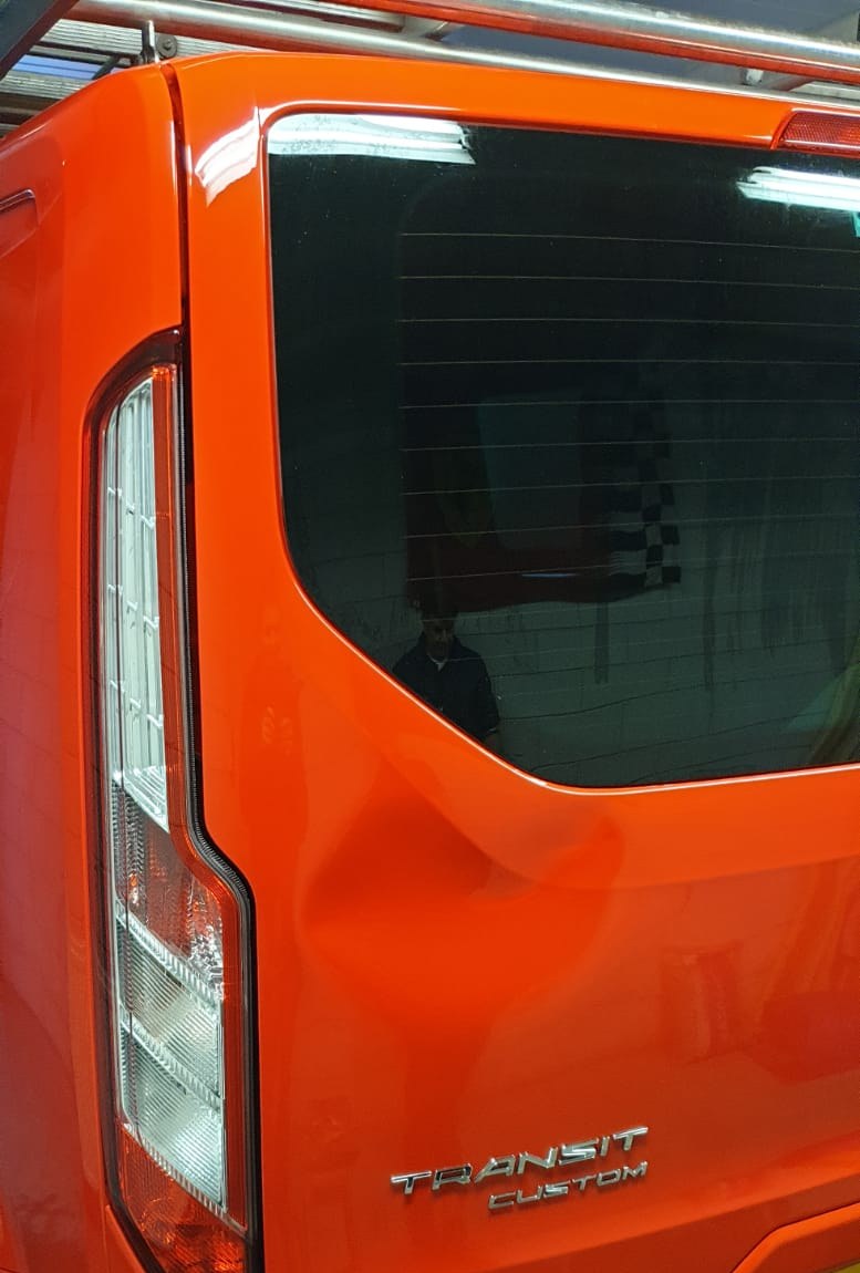 Achterkant van een oranje Ford Transit Custom